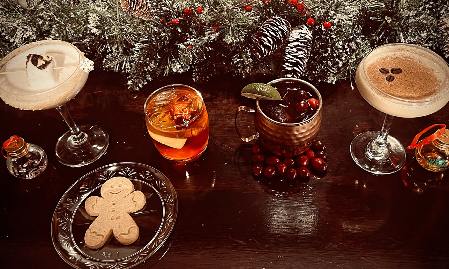 Four festive cocktails on a bar with winter decorations