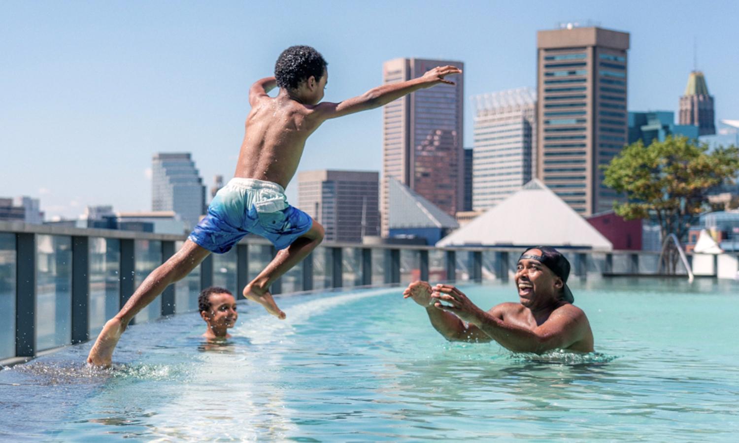 Child jumping into fathers arms at a hotel pool