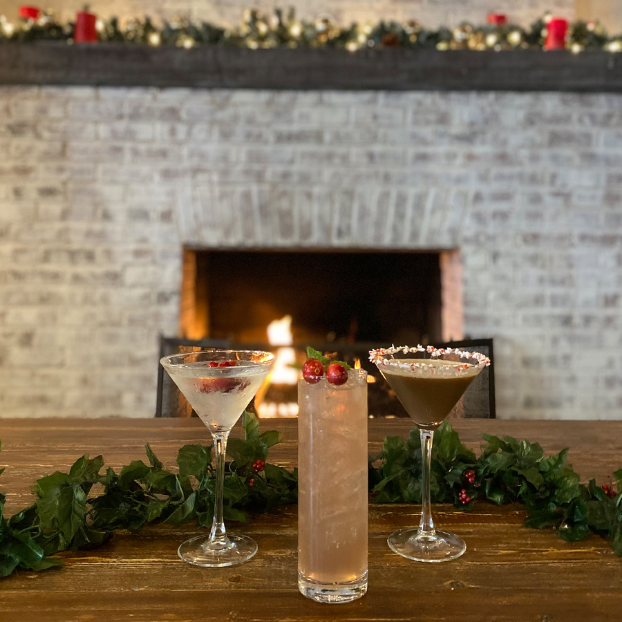 Three cocktails in front of a lit fireplace