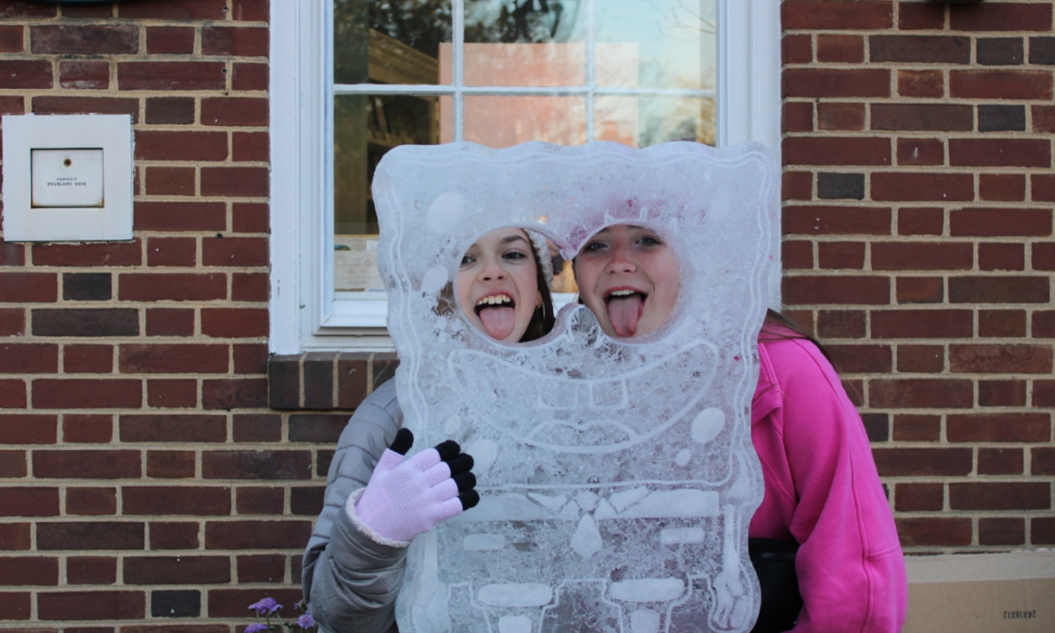 Two kids taking a photo with an ice sculpture