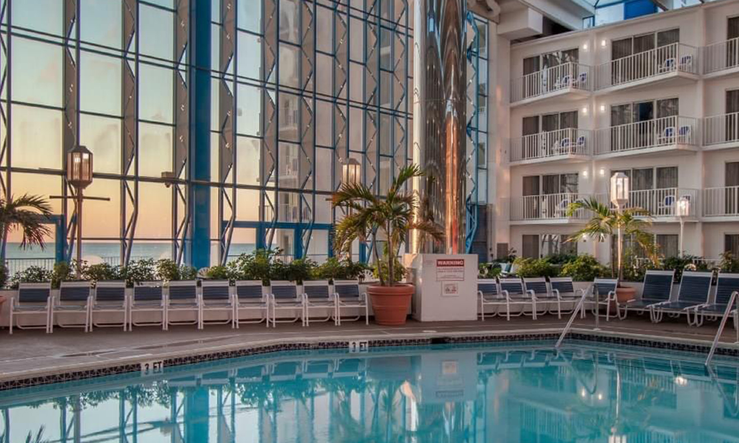 Inside of resort at the pool with giant glass wall with sunset view