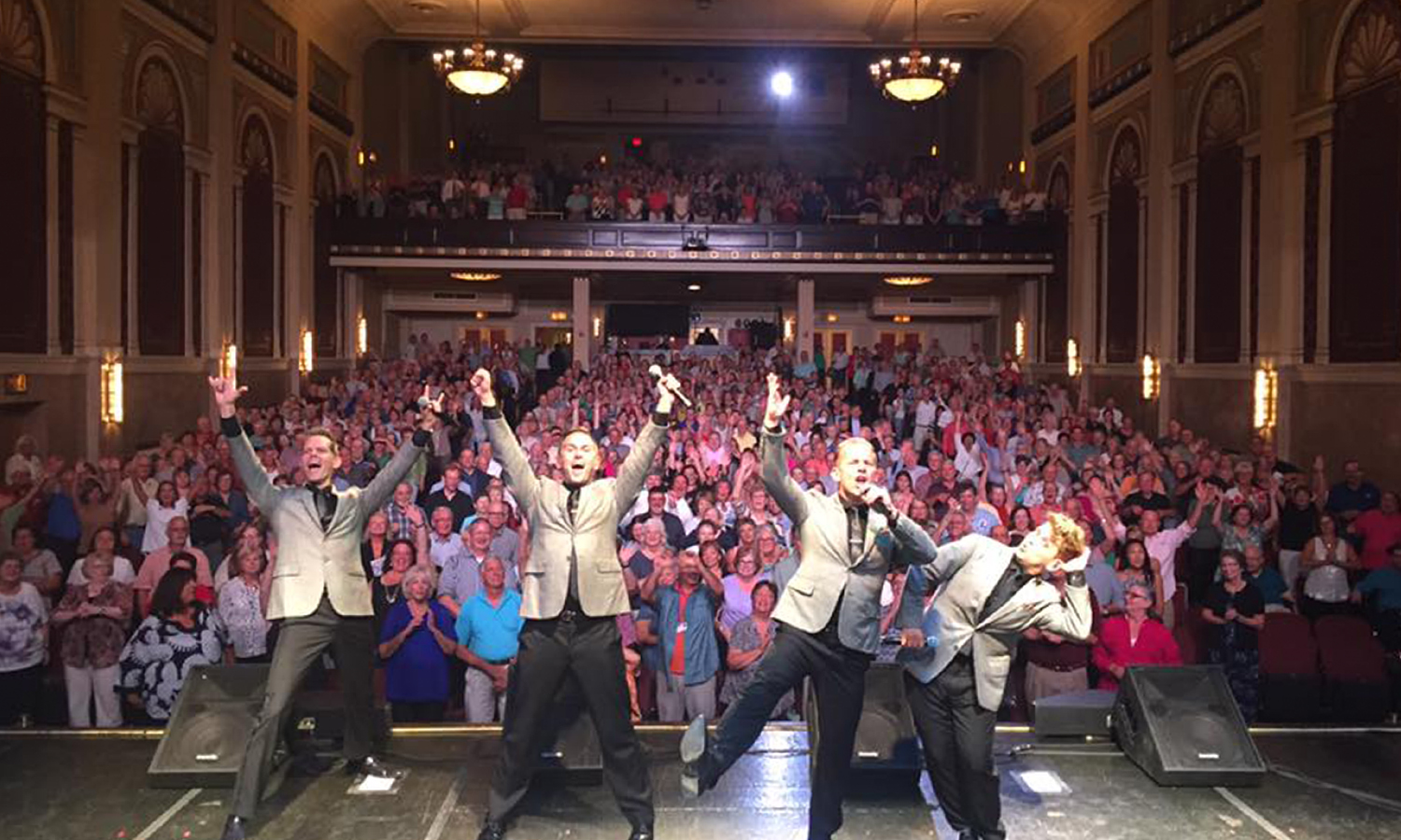 Performance group celebrating on stage in front of packed crowd