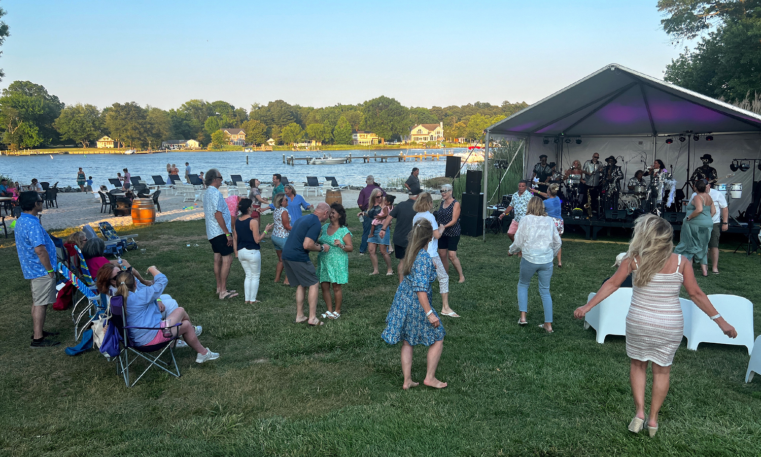 People enjoying an outdoor concert by the water